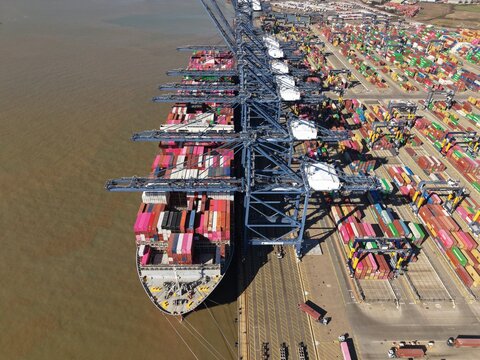 Aerial view of container ships berthed at the Port of Felixstowe, a symphony of steel and cargo against the tranquil water, Felixstowe, Felixstowe, United Kingdom.