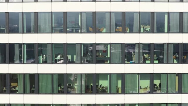 Revealing cityscape of Bielefeld from behind office building windows while descending, capturing daily business life