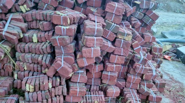 Stack of old red clay bricks tied in bundles at a construction site, showing reused building material piled together.