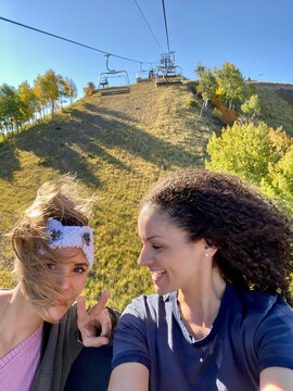 Two smiling woman sitting side by side on a chair lift in summer, Sundance, Utah, USA