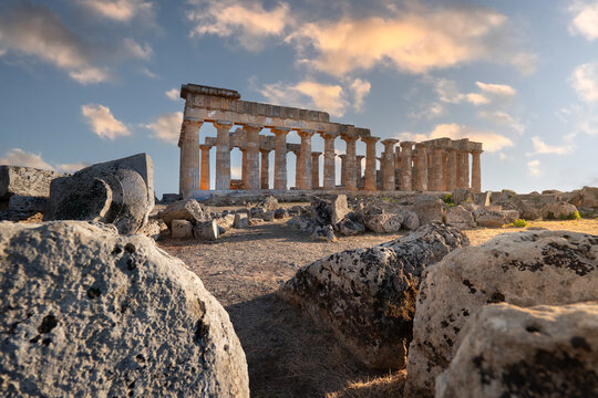 View of the ancient Greek Temple of Hera at Selinunte Archaeological Park with scattered stone ruins and a dramatic sunset sky Marinella, Sicilia, Italy.