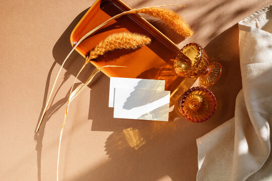 Overhead view of two blank business cards on a ceramic tray next to egg cups and dried pampas grass with a linen napkin on a table