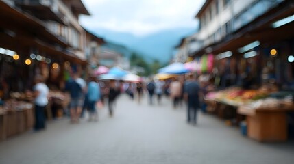 Obraz premium Blurred view of a bustling outdoor market street with vendors and shoppers against a mountain backdrop
