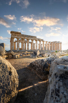 View of the ancient Greek temple ruins at Selinunte Archaeological Park with Doric columns and scattered stones under a soft sky in Marinella, Sicilia, Italy.