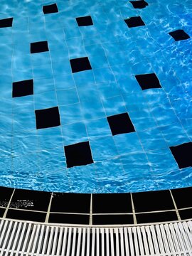 Full frame close-up of the edge of a tiled swimming pool with an overflow grate
