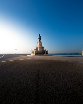 View of the statue of King Jose I in Praca do Comercio with long shadows on the paved square under a clear blue sky in Lisbon, Lisbon, Portugal.