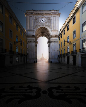 View of the Rua Augusta Arch framed by yellow historic buildings and a patterned stone pavement in Lisbon, Lisbon, Portugal.