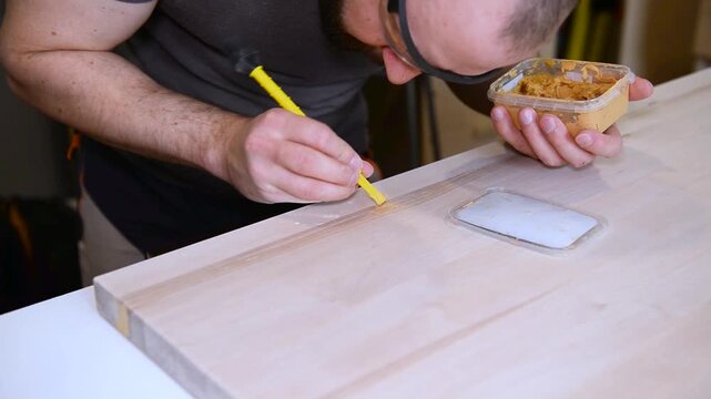 Manually using tools for renovation at the joinery. Joiner manually deals with woodwork products renovation. Carpenters worker manually renovating products the using woodwork putty