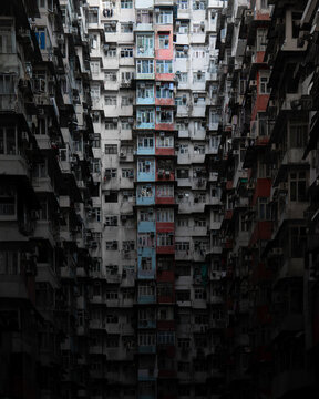 View of the densely packed residential facade of the Yick Cheong Building with colorful windows and air conditioning units in Hong Kong.