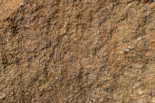 Natural orthogneiss rock surface with rough texture and visible mineral grains. Ideal as a background or for geology, construction, nature and texture design projects with earthy tones.
