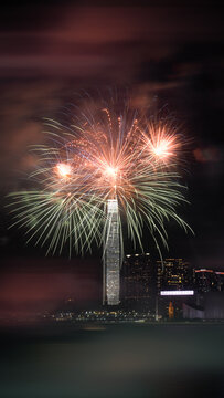 View of colorful fireworks exploding over the International Commerce Centre and the city skyline at night in Hong Kong.