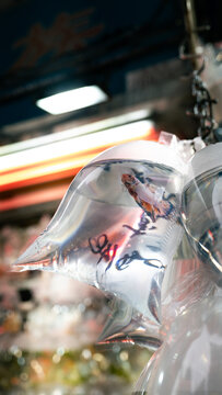 View of a colorful ornamental fish swimming inside a clear plastic bag at a traditional street market Hong Kong.