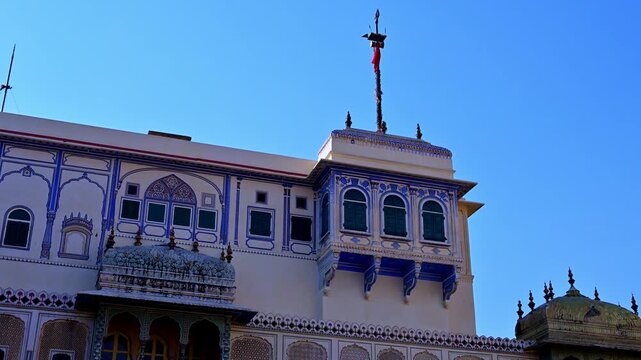 View of Chandra Mahal inside City Palace Jaipur showing blue and white Rajput architecture with decorated windows, balcony facade, palace flag on top indicating royal residence in Jaipur Rajasthan.