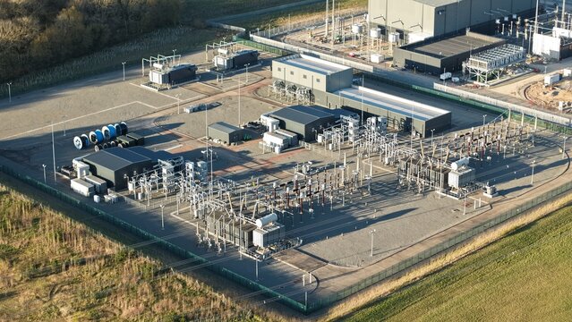 Aerial view of a sprawling Bramford substation with silver structures amid the muted landscape, a testament to power and engineering prowess, Ipswich, United Kingdom.