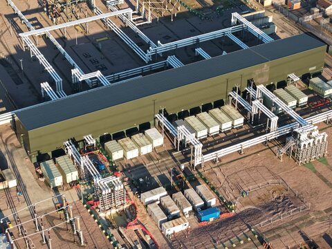 Aerial view of the Bramford Substation, a landscape of industrial geometry where metallic structures meet muted tones under the open sky, Ipswich, United Kingdom.