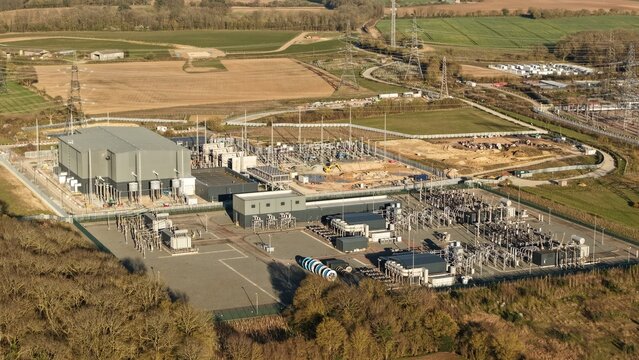 Aerial view of National Grid Bramford substation, a symphony of steel and power amidst the verdant landscape, Ipswich, United Kingdom.