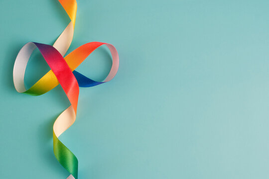 Rainbow Infinity Satin Ribbon on Blue Background Representing Autism Acceptance and Neurodiversity Concept