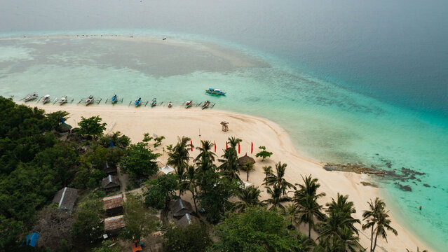 Aerial view of turquoise waters meet the white sands of a tropical island paradise, boats dotting the shoreline, Virgin Island, Bantayan, Cebu, Philippines.