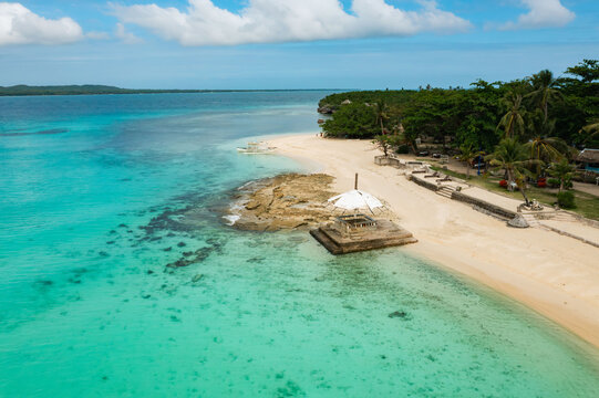 Aerial view of the sandy beach with crystal-clear turquoise waters meeting the shore near lush green vegetation, Virgin Island, Bantayan, Cebu, Philippines.