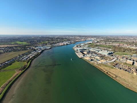 Aerial view of the River Orwell winding past the industrial port, where the bright water meets the darker earth, Ipswich, United Kingdom.
