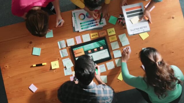 Time lapse of business people working together to design web design. Aerial view of designer brainstorming and discussing about website interface and looking at tablet with digital design. Symposium.