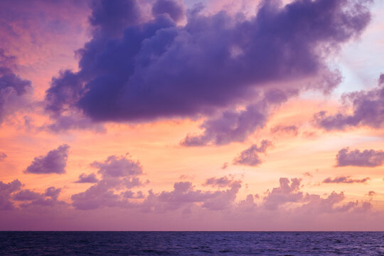Pastel sunset sky over ocean with purple clouds and calm horizon