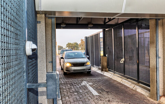 Silver Sedan Driving Through  mesh security gate an Automatic Security Gate Entrance