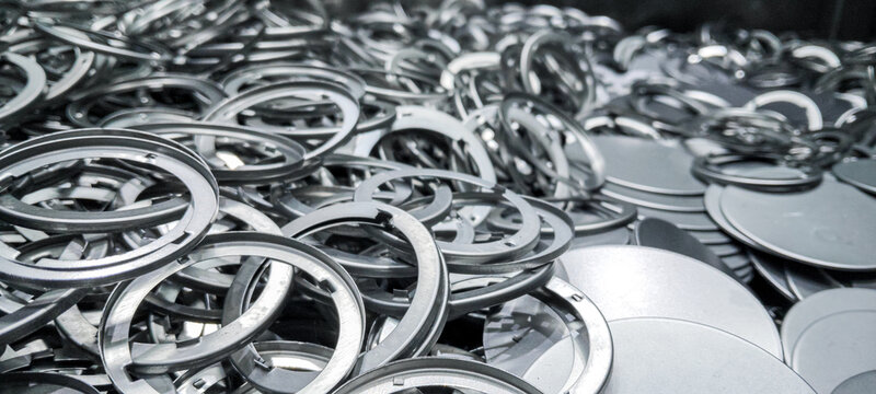 Pile of industrial metal rings and circular steel components in factory.