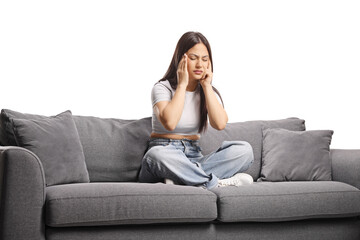 Fototapeta premium Stressed young woman sitting on a sofa and holding her head