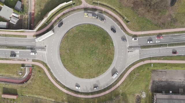 Genk, Belgium. Top-down drone hoovering over busy roundabout with flowing traffic and transport vehicles