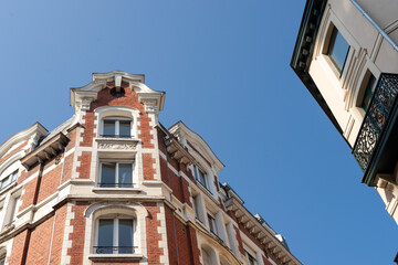 Low angle view of historic red brick and white stone residential building facades in Lille against a clear blue sky. © dsbedarieva