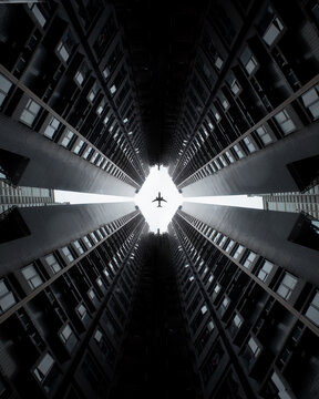 View of an airplane flying through a diamond-shaped gap between towering residential skyscrapers in Hong Kong.