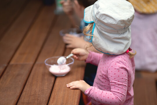 Kindergartenkinder essen ihren Nachtisch drau&szlig;en im Garten