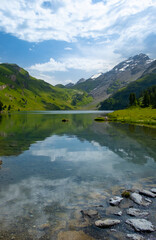 Fototapeta premium Discover the beauty of Engstlensee Lake in Switzerland. Clear waters reflect surrounding mountains and greenery, showcasing a serene natural landscape. Travel destination and popular trail.