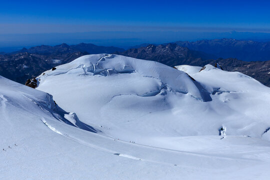 Mountain glacier panorama of Monte Rosa massif with summit Parrotspitze and rope teams of mountaineers seen from Zumsteinspitze in Pennine Alps, Switzerland