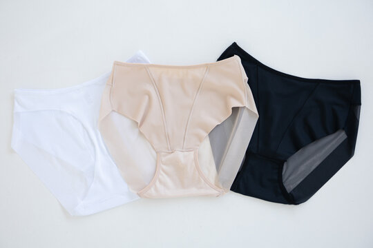 Women's panties on a white background: white, beige, black. Basic colors women's briefs slips on a light background, top view
