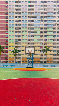View of the iconic basketball court at Choi Hung Estate with its colorful residential facade and palm trees in Hong Kong.