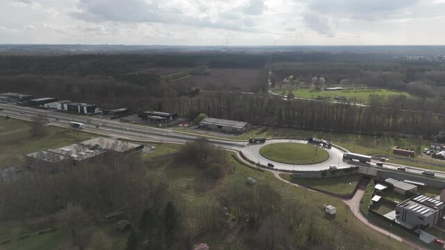 Genk, Belgium. Aerial drone footage of roundabout with traffic and suburban landscape under cloudy sky