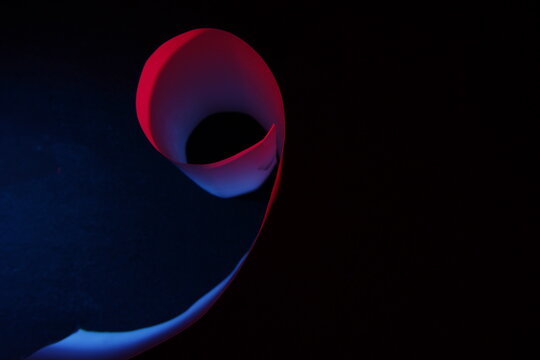 Curvas de papel para impresora con luz lateral de color rojo y azul, forman un cilindro con el ala desplegada,  presentan un hermoso dise&ntilde;o abstracto  con fondo negro.