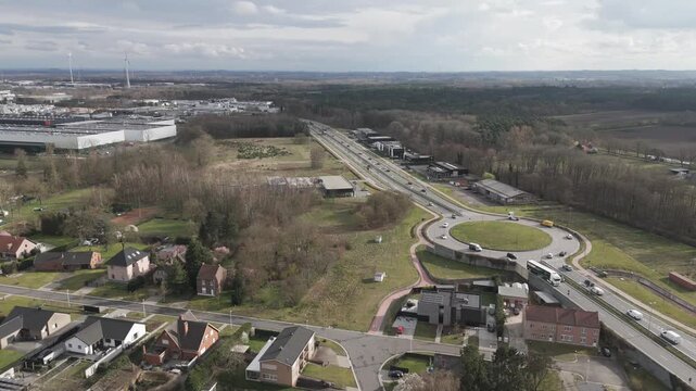 Genk, Belgium. Aerial drone movement revealing suburban neighborhood transitioning into industrial zone with wind turbines