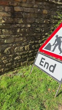 Vertical video social media - A standing UK traffic warning sign with red border, bearing an icon of a person digging, with the word END, to show where nearby roadworks have finished.