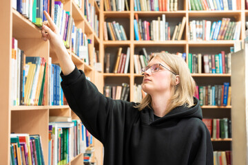 Young man browsing bookshelves in library