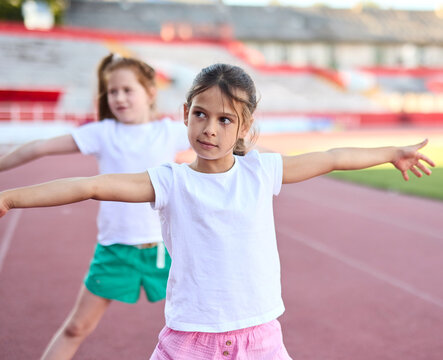 Children exercising and stretching  at the stadium, practice during sports class in school training, little boys and girls in sportswear training as athletes outdoor. Concept of sport, fitness and ach