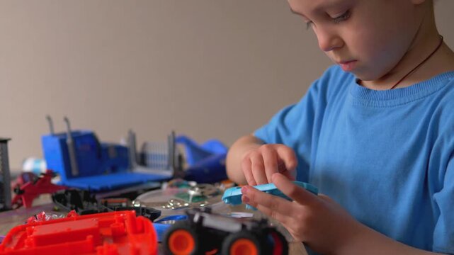 Focused Young Boy Inserting Red AA Battery into Electronic Toy, Child Repairing Gadget at Home Desk, Practical Skills and STEM Learning for Kids