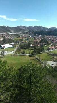 Elevated view of a mountain valley settlement with red-roof houses from Orlov Kr&scaron; in Cetinje. Illustrates terrain-constrained urban layout, low-rise density pattern, and landscape-adapted development.