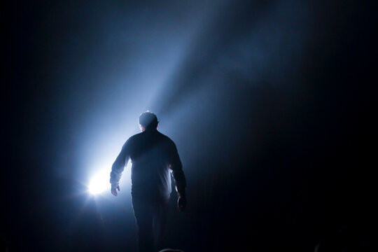 Person Walking Toward Light in Dark Tunnel Symbolizing Hope and Transition