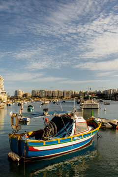 Colorful luzzu boats bobbing gently in Spinola Bay under a bright sky