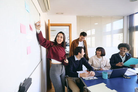 Diverse Group of young latin professionals engaged in a discussion at an office, hispanic teamwork using laptop at workplace 