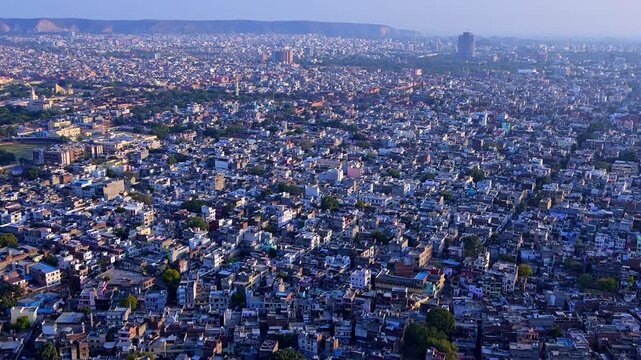 Wide aerial view of Jaipur city from Nahargarh Fort showing dense houses, Jantar Mantar area, Sawai Mansingh Stadium side, Aravalli hills and panoramic skyline.
