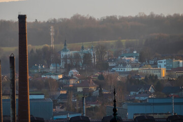 Panorama Ostrowca Świętokrzyskiego w Polsce, z kościołem św. Mikołaja w Szewnej wyraźnie widocznym w centrum. Kościół, z charakterystycznymi kopułami W tle krajobraz -  wzgórza i Góry Świętokrzyskie © Grzegorz